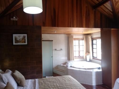 a bathroom with a tub and a bed in a room at Pousada Mon Desir in Penedo