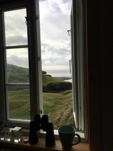 a window with a view of a green field at Idyllic house near river and ocean in Leynar