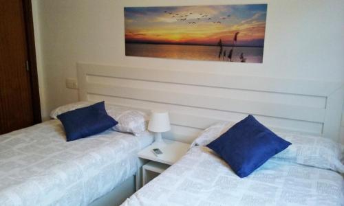 タリファにあるBonito, luminoso, cerca del mar con Parkingのベッドルーム1室(ベッド2台付)が備わります。壁には絵画が飾られています。