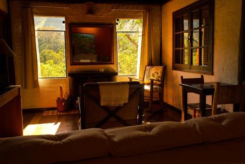 a living room with a couch and two windows at Pousada Vila Santa Barbara in São Francisco Xavier