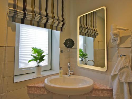 a bathroom with a sink and two mirrors at Hotel Am Steendamm in Oyten