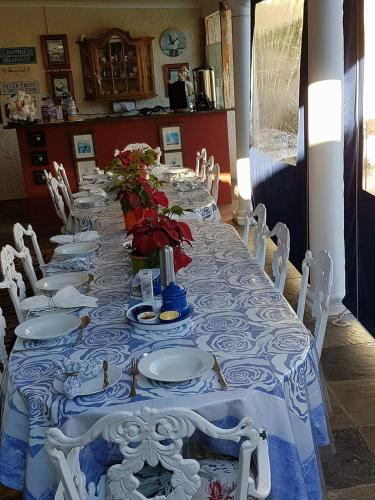 a long table with white plates and flowers on it at Mulligans Guest Lodge in Hermanus