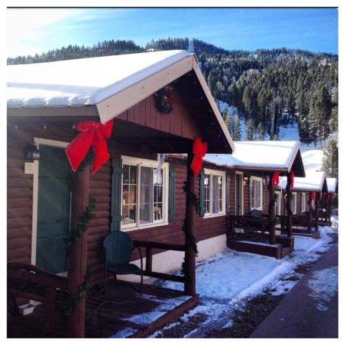 a log cabin with christmas bows on it in the snow at Three Bears Lodge in Red River