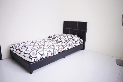 Bett in einem weißen Zimmer mit einer schwarzen und rosa Tagesdecke in der Unterkunft Arau Idaman Homestay in Arau