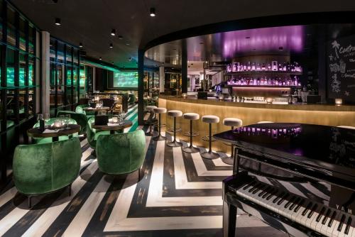 a bar with green chairs and a piano at Central Plaza in Zurich