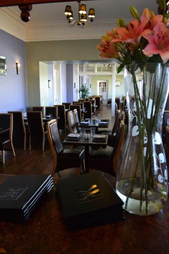 a restaurant with tables and chairs and a vase of flowers at Stotfield Hotel in Lossiemouth
