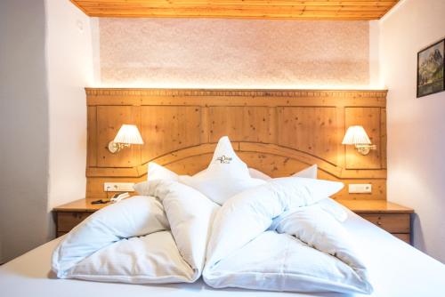 a bed with white pillows on top of it at Alpin Garni die kleine Post in Solda