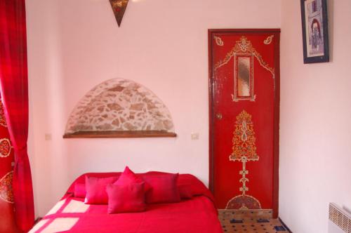 
a bed room with a red bedspread and a red wall at Riad Le Grand Large in Essaouira
