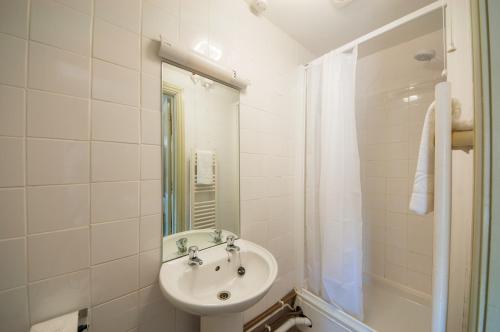 a white bathroom with a sink and a shower at The Old Inn in Mullion