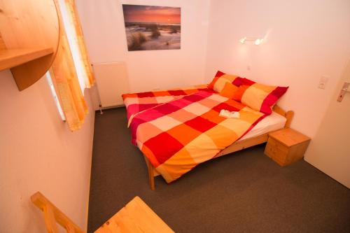 ein kleines Schlafzimmer mit einem Bett mit einer bunten Bettdecke in der Unterkunft Wangeroogeweg 5a in Schillig