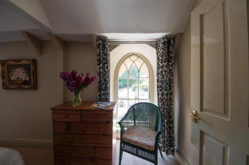 a bedroom with a dresser and a window and a chair at The Old Inn in Mullion
