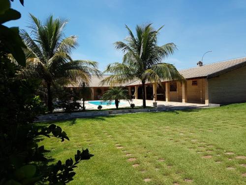 a house with a yard with palm trees and a swimming pool at Chacara Recanto dos Passaros 01 in Olímpia