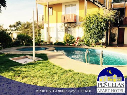 a swimming pool in a yard next to a building at Apart Hotel Penuelas in Coquimbo