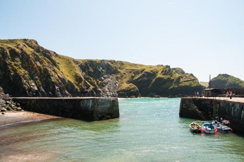 a group of boats in the water next to a mountain at The Old Inn in Mullion