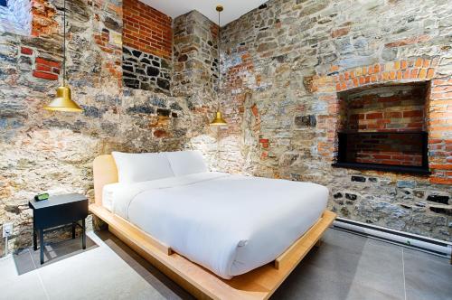 een bed in een kamer met een bakstenen muur bij Les Lofts Notre-Dame - Par Les Lofts Vieux-Québec in Québec