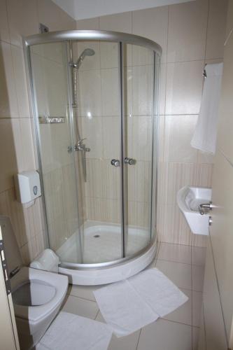 a bathroom with a shower and a toilet and a sink at Hotel Piazza in Peshkopi