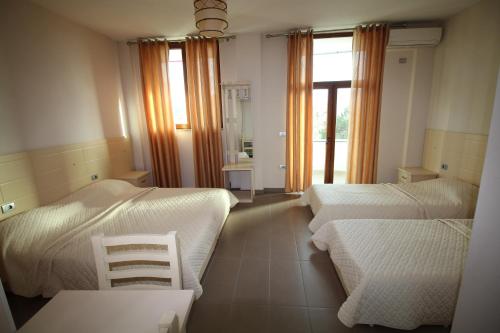 a bedroom with two beds and two chairs and a window at Hotel Piazza in Peshkopi
