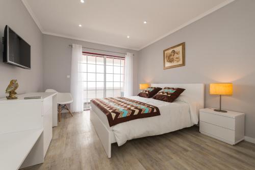 a bedroom with a bed and a desk and a television at Ilhéu do Areeiro in Madalena