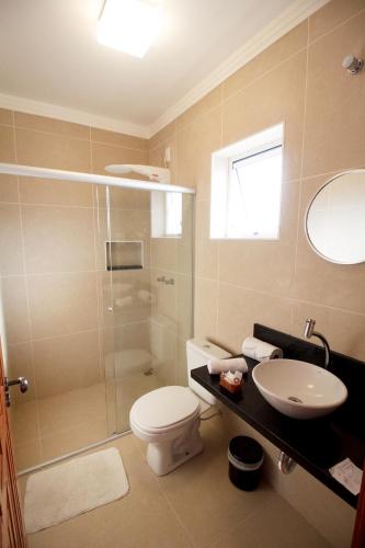 a bathroom with a shower and a toilet and a sink at Pousada Acqua Azul in Bertioga