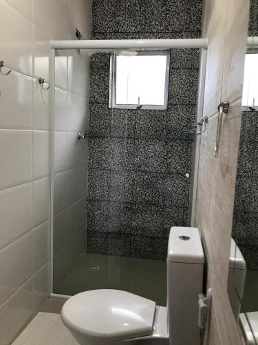a bathroom with a toilet and a shower with a window at Camping Pousada Ilha do Mel - Frente ao Mar in Boracéia