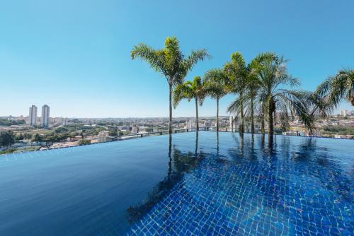 a swimming pool with palm trees in a city at I am Design Hotel Campinas by Hotelaria Brasil in Campinas