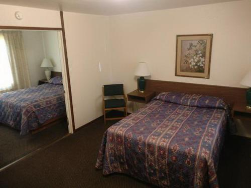 a hotel room with two beds and a desk and a mirror at Lakeside Motel in Moses Lake