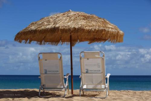 費爾南多迪諾羅尼亞的住宿－Casa Conceição，海滩上一把遮阳伞下的两把椅子