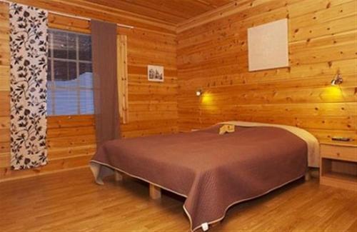 um quarto com uma cama num quarto de madeira em Särkijärven Majat em Muonio