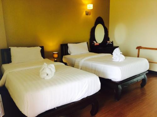 two beds in a hotel room with towels on them at Baan Sang Singh in Chiang Mai