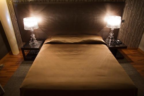 a bedroom with a large bed with two lamps on it at Hotel Aleramo in Asti