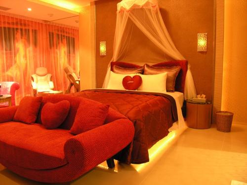 a bedroom with a bed and a red couch at Miho Boutique Motel in Zhonghe
