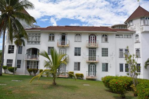 a large white building with windows and a palm tree at Seacastles by the beach/pool in Montego Bay