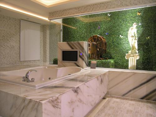 a large bathroom with a tub and a tv on a wall at Miho Boutique Motel in Zhonghe