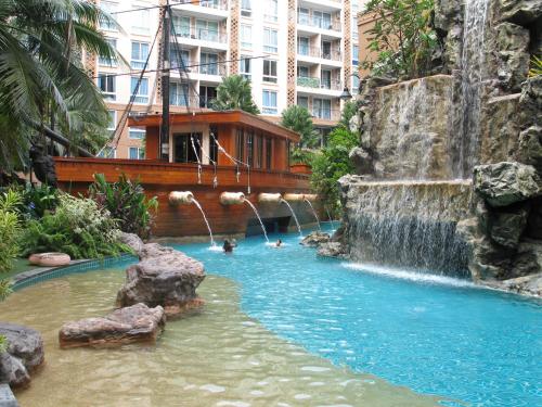 a pool in a hotel with a waterfall and people in it at Atlantis Condo Resort in Jomtien Beach