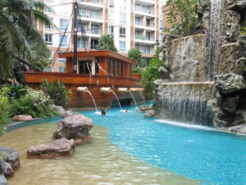 una piscina en un hotel con una cascada y gente en ella en Atlantis Condo Resort en Jomtien Beach