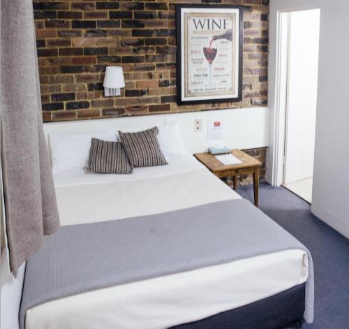 a bedroom with a bed and a brick wall at Hornsby Inn in Hornsby