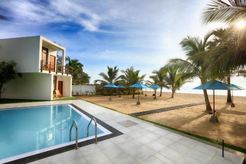 a villa with a swimming pool next to the beach at Arugambay Roccos in Arugam Bay