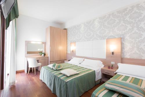 a hotel room with two beds and a desk at Michelangelo Cesenatico in Cesenatico