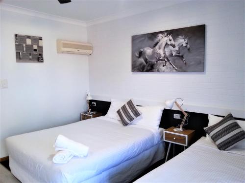 two beds in a room with white walls at Kurri Motor Inn in Kurri Kurri