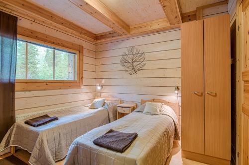 two beds in a room with wooden walls at Karhun Maja in Ruka