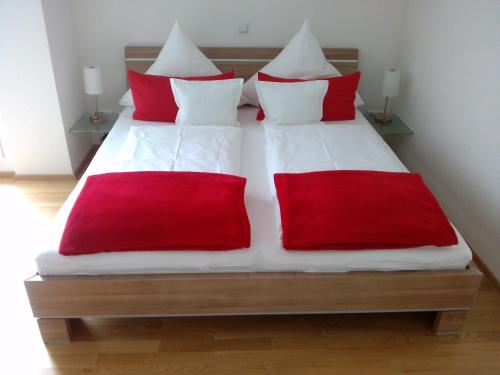 a bed with red and white sheets and red pillows at Ferienwohnung Susanne Kiefer in Nonnenhorn