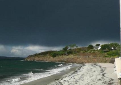 a beach with a cloudy sky and the ocean at Hôtel Kermor in Concarneau
