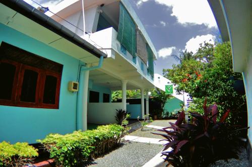 a blue and white building with a balcony and plants at Tamara Motels in Hikkaduwa