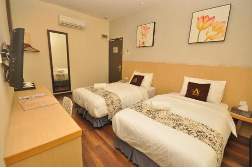 a hotel room with two beds and a television at Art Cottage Hotel in Ipoh