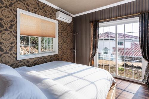 a bedroom with a bed and a large window at Mar En Luz in Seogwipo