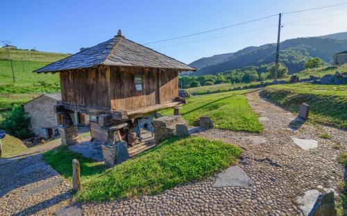 a small wooden building on a hill with a road at A Casoa II in Santa Eulalia de Oscos