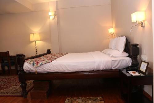 a bedroom with a bed with white sheets and two lamps at The Heritage Club - Tripura Castle Hotel and Spa in Shillong