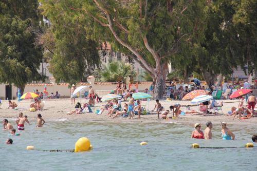 a group of people on a beach with people in the water at Hotel Trabuco in Santiago de la Ribera