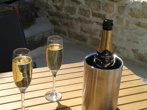 - une bouteille de champagne et deux verres sur une table dans l'établissement La Maison Tumtum Arbre, à Loudun