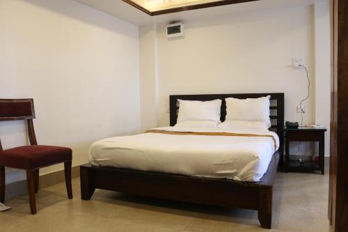 a bed in a room with a red chair and a bed sidx sidx at The Heritage Club - Tripura Castle Hotel and Spa in Shillong